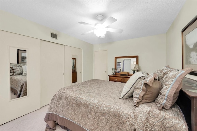 bedroom featuring light carpet, a closet, ceiling fan, and a textured ceiling