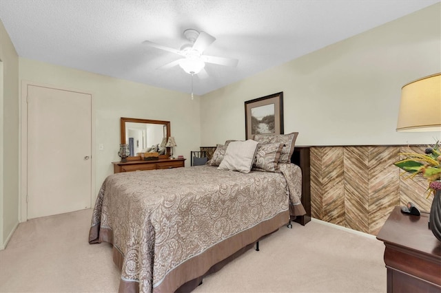 carpeted bedroom featuring ceiling fan and a textured ceiling