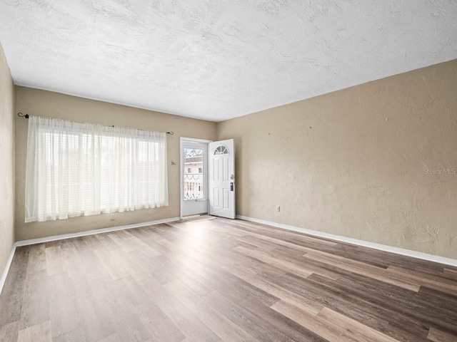 empty room featuring a textured ceiling and light wood-type flooring