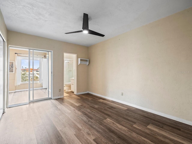 empty room featuring ceiling fan, wood-type flooring, a textured ceiling, and a wall unit AC