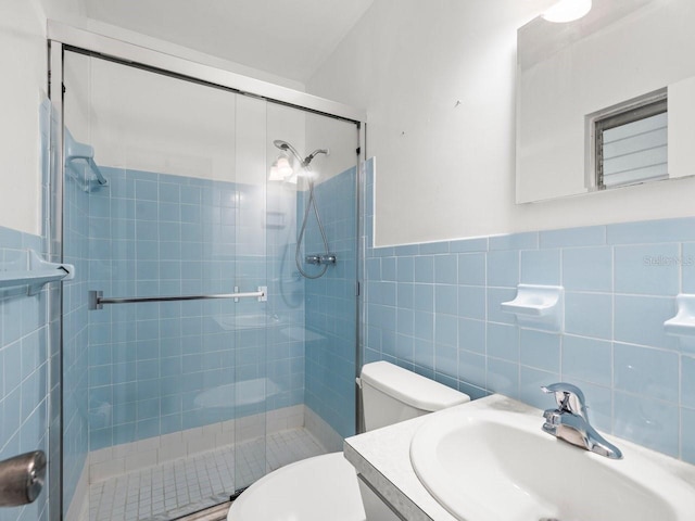 bathroom with vanity, a shower with door, toilet, and tile walls