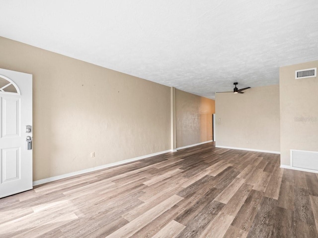 empty room featuring a textured ceiling, light hardwood / wood-style flooring, and ceiling fan