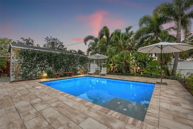 pool at dusk with a patio area