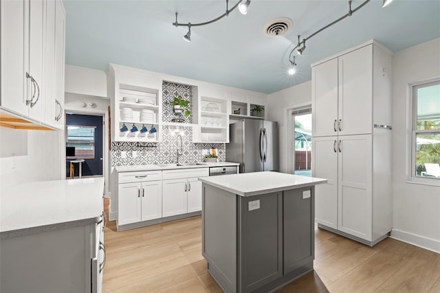 kitchen with sink, backsplash, white cabinets, a kitchen island, and stainless steel appliances