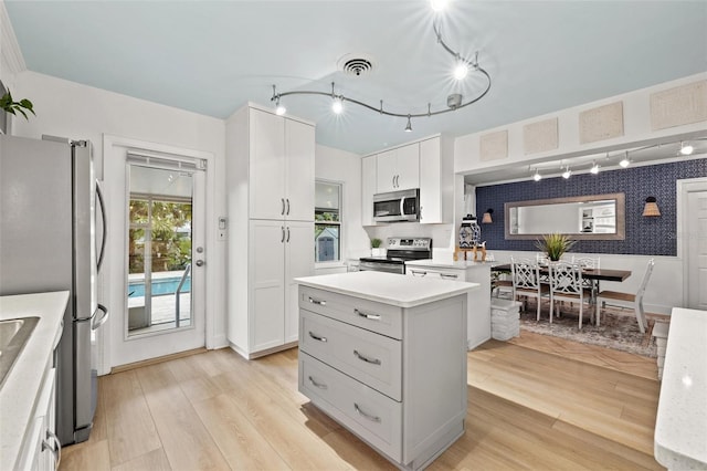 kitchen with white cabinets, light hardwood / wood-style floors, and appliances with stainless steel finishes