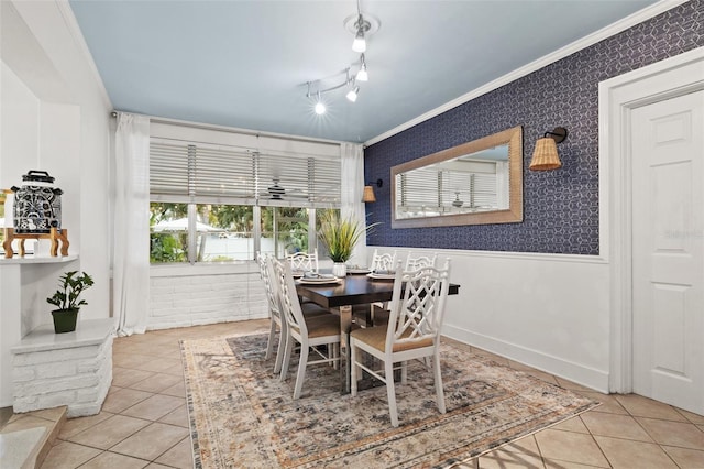 tiled dining room featuring rail lighting and crown molding