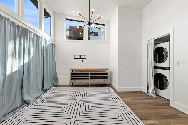 bedroom with dark hardwood / wood-style floors, stacked washer / dryer, a high ceiling, and a chandelier