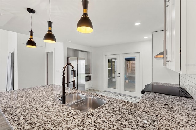 kitchen featuring french doors, sink, backsplash, kitchen peninsula, and decorative light fixtures