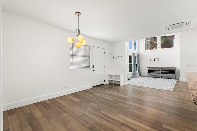 unfurnished living room featuring a notable chandelier, plenty of natural light, and dark hardwood / wood-style flooring