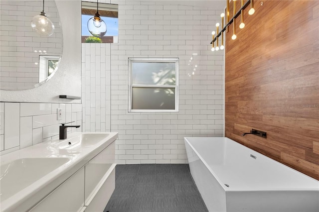 bathroom featuring tile patterned flooring, a washtub, tile walls, and vanity