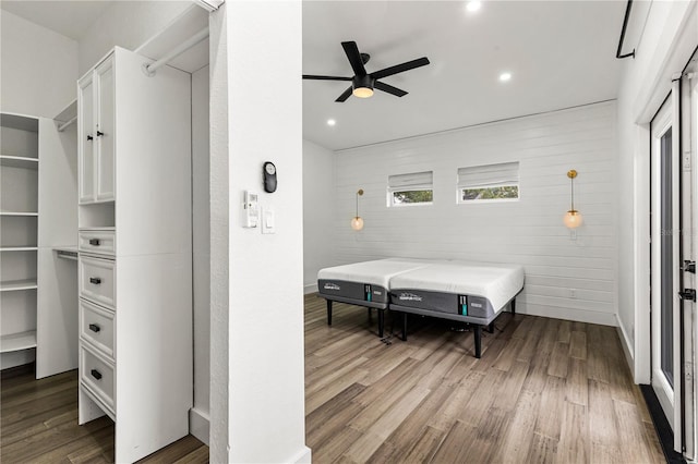 bedroom featuring wood-type flooring, ceiling fan, and wooden walls