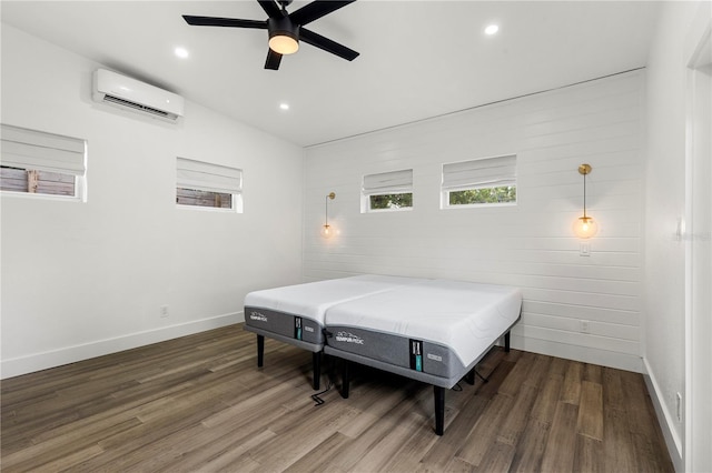 bedroom with dark hardwood / wood-style flooring, an AC wall unit, and ceiling fan