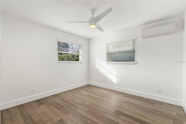 unfurnished room featuring hardwood / wood-style floors, a wall unit AC, and ceiling fan