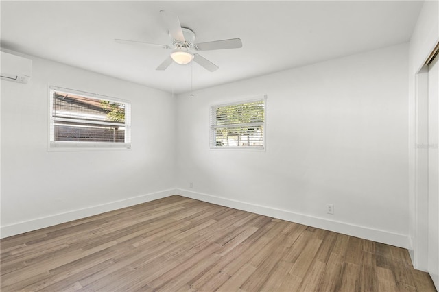 empty room featuring light hardwood / wood-style floors, a wall unit AC, and ceiling fan