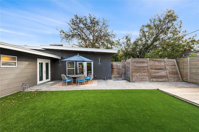 back of house featuring a lawn, a patio, a wooden deck, and french doors