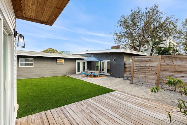 rear view of property featuring french doors, a patio area, and a lawn