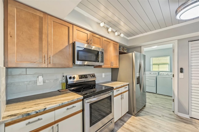 kitchen featuring washer and dryer, wooden ceiling, stainless steel appliances, light hardwood / wood-style floors, and backsplash