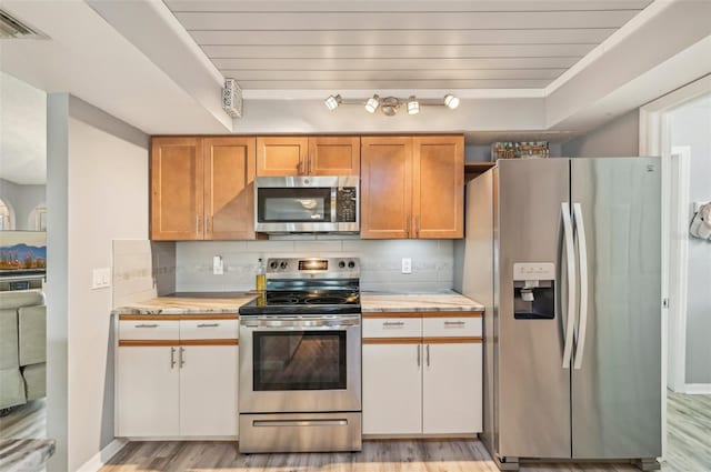 kitchen with stainless steel appliances, white cabinetry, light wood-type flooring, and decorative backsplash