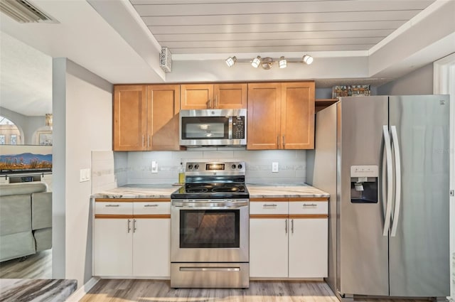 kitchen featuring white cabinetry, appliances with stainless steel finishes, light hardwood / wood-style floors, and decorative backsplash