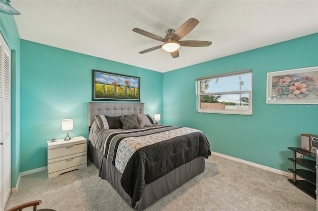 bedroom featuring ceiling fan, light colored carpet, and a textured ceiling