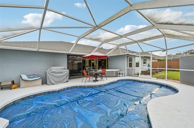 view of pool with a jacuzzi, a patio area, and glass enclosure