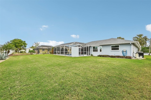 rear view of house featuring glass enclosure and a lawn