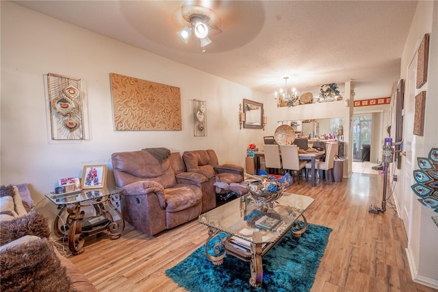 living room with a textured ceiling, hardwood / wood-style floors, and ceiling fan with notable chandelier