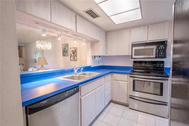 kitchen with pendant lighting, sink, light tile patterned floors, appliances with stainless steel finishes, and a chandelier