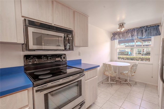 kitchen featuring stainless steel electric stove, light brown cabinets, and light tile patterned floors