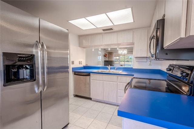 kitchen featuring appliances with stainless steel finishes, sink, light brown cabinets, light tile patterned floors, and an inviting chandelier