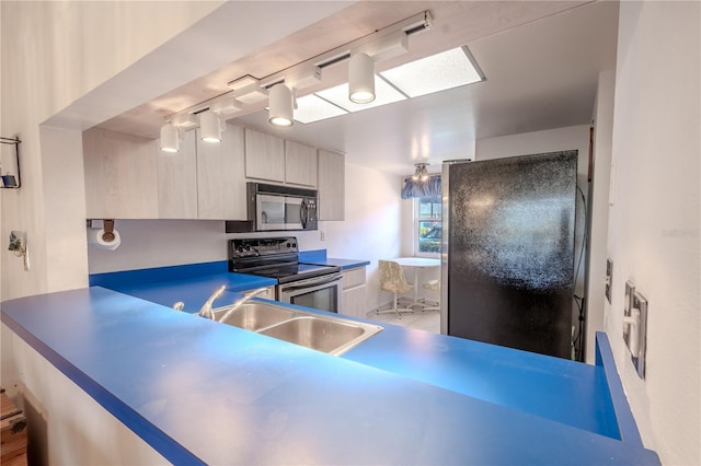 kitchen with black refrigerator, kitchen peninsula, stainless steel range with electric cooktop, and sink