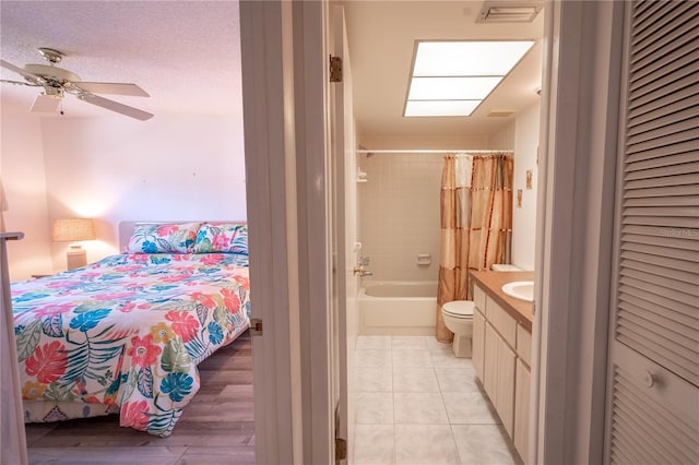 bedroom with ceiling fan, light tile patterned floors, and ensuite bath