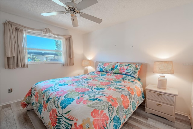 bedroom with ceiling fan, wood-type flooring, and a textured ceiling