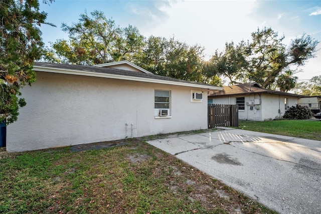 rear view of property featuring a patio, cooling unit, fence, a lawn, and stucco siding