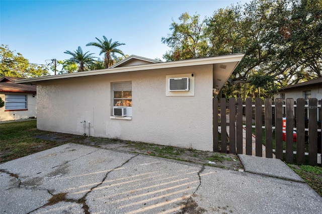 view of side of property featuring cooling unit, a patio area, fence, and stucco siding