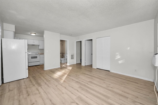 unfurnished living room with light wood-style floors, a textured ceiling, and baseboards