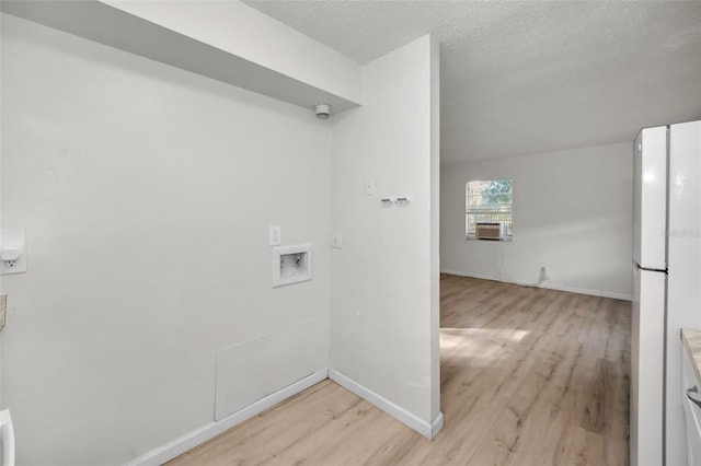 clothes washing area with laundry area, baseboards, cooling unit, a textured ceiling, and light wood-type flooring