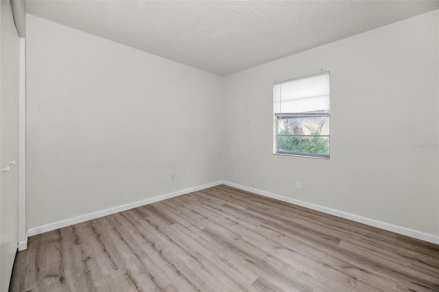 unfurnished room featuring light wood-style floors, baseboards, and a textured ceiling