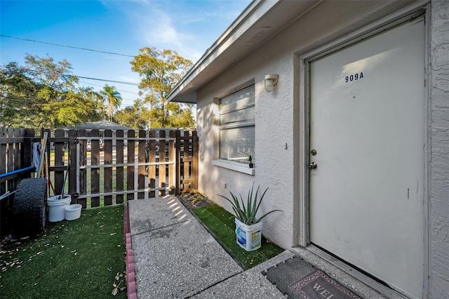 view of exterior entry featuring fence and stucco siding