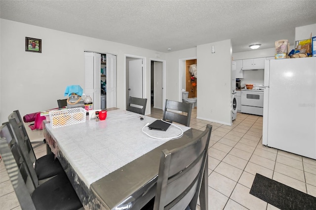 dining space with light tile patterned floors, baseboards, a textured ceiling, and washer / dryer