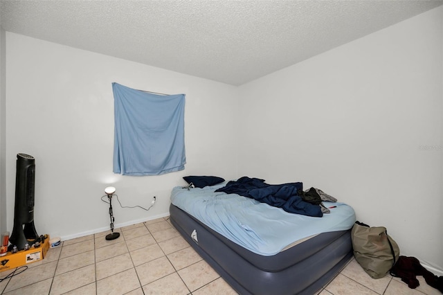 bedroom featuring light tile patterned floors, a textured ceiling, and baseboards