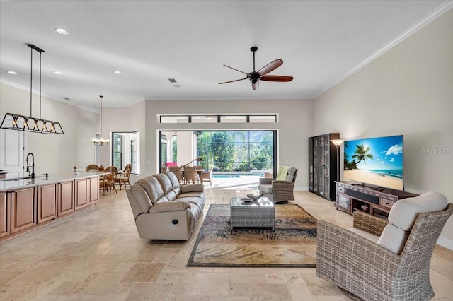 living room featuring ceiling fan with notable chandelier, ornamental molding, and sink