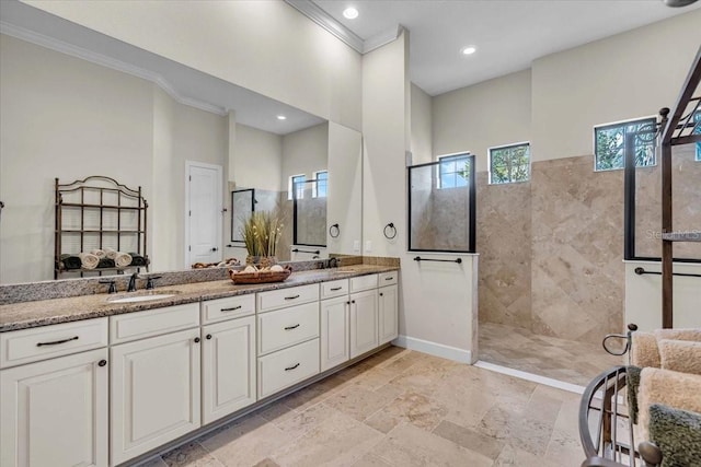 bathroom with a tile shower, vanity, plenty of natural light, and crown molding