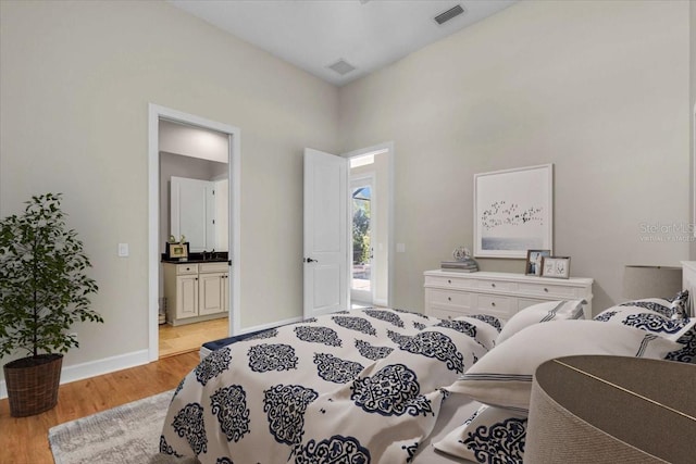 bedroom with ensuite bathroom and light hardwood / wood-style flooring