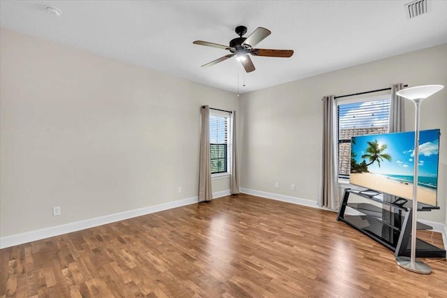 unfurnished living room featuring ceiling fan, plenty of natural light, and wood-type flooring