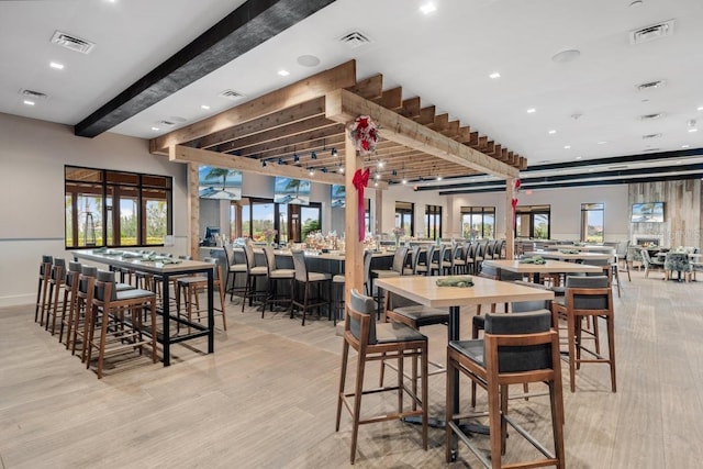 dining room featuring beam ceiling and light hardwood / wood-style floors