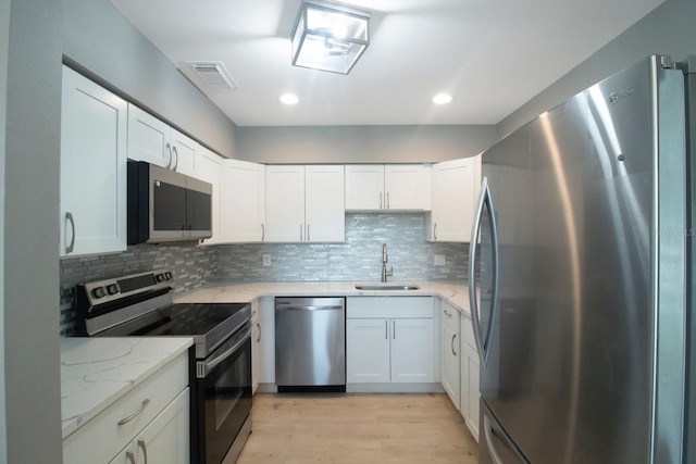 kitchen featuring sink, light stone countertops, white cabinets, and appliances with stainless steel finishes