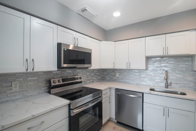 kitchen with light stone counters, sink, stainless steel appliances, and white cabinets