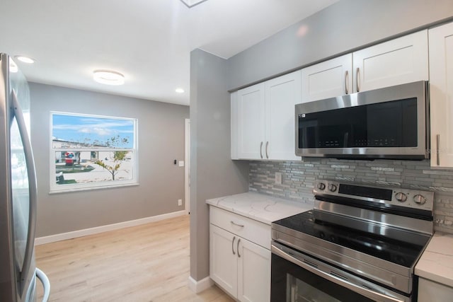 kitchen with decorative backsplash, light stone countertops, white cabinets, and appliances with stainless steel finishes