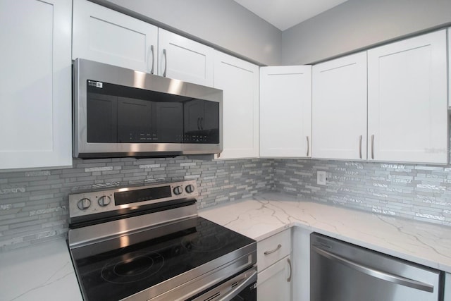 kitchen featuring white cabinetry, appliances with stainless steel finishes, light stone countertops, and backsplash